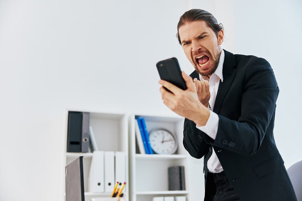 Maximizando Vendas pelo WhatsApp: Estratégias e Scripts Eficazes 4 Homem bravo com celular na mão porque não realizou vendas pelo whatsapp
